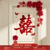 Nueva decoración de habitación de bodas estilo chino, con caracteres auspiciosos, decoraciones festivas para puertas, borlas y arreglos florales, creando un telón de fondo pintoresco para las fotos de boda.