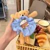La linda scrunchie de oso a cuadros azules para niños es extremadamente elegante para recoger el cabello en un moño, dando un aspecto de alta gama