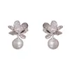 Diseño retro, moderno y minimalista con gruesos pétalos de metal plateado y perlas - aretes únicos y elegantes para mujer, disponibles para venta al por mayor