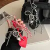 Colgante de cuero con forma de corazón lindo y femenino, disponible en stock transfronterizo, con cuentas de plata, lazo y elementos de corazón combinados en un accesorio para llavero