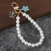 Chaveiro de pérolas estilo Chanel com pingente de flor, chaveiro anti-perda, capa para fones de ouvido, acessório para bolsa de celular