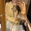 Cardigã de tricô elegante e chique estilo francês com acabamento em renda, apresentando um design jovem, laço em formato de coração e detalhes de amarração para mulheres
