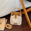 Bolso de paja tipo cubo nuevo estilo vacación de verano en la playa 2026, con un fresco diseño de patchwork en colores contrastantes y una textura tejida simple, un bolso para mujer