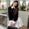 Look préppy para o início do outono: um conjunto de duas peças composto por um suéter cardigã falso de duas peças com blocos de cor e uma meia-saia plissada