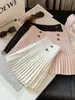Falda corta de lana estilo coreano con hebilla dorada para mujer 2026 Otoño/Invierno Nueva falda plisada de línea A versátil de cintura alta adelgazante anti-exposición