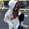 Roupas de inverno 2026 nova blusa de moletom estilosa e que rejuvenesce, com estampa de letras estilo americano e mangas compridas para mulheres, jaqueta com capuz de caimento solto para outono, moderna