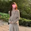 Top negro de hombros descubiertos para mujer hecho de hilo core-spun, con un diseño único, corte ajustado y estilo elegante, combinado con un suéter de punto de manga larga