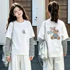 Camiseta de manga comprida com desenho para meninas, conjunto de duas peças de outono, novo estilo 2026, para crianças de tamanho médio e grande, camada base de algodão puro