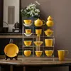 Juego de té de cerámica amarillo limón con detalles dorados, que incluye una taza con tapa, tetera, taza de maestro, taza de degustación, taza de té, soporte para tetera, posavasos y taza de equidad