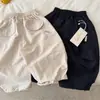 Pantalones largos para niños 2026 nuevo producto de verano, pantalones unisex de color liso con cordón y letras, pantalones curvos versátiles para niños pequeños