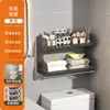 Baño de estilo abierto con un inodoro, un soporte para pañuelos de papel y toallitas húmedas encima del inodoro, y un estante de pared para toallas perfumadas
