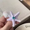 Pinza para el pelo con forma de estrella de mar y concha de perla, estilo resort costero, incrustada de diamantes, sensación de lujo ligero y alta gama, accesorio de moda para el cabello para mujer