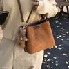 Bolso de hombro estilo coreano para el otoño de 2026, con un pequeño charm de oso, un bolso tipo cubo nuevo y elegante para mujer, simple y versátil