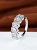 Anillo de banda delgada, estilo explosivo cruzado, totalmente pavimentado con una hilera de circonitas cúbicas en forma de ojo, incrustado con pequeños diamantes ovalados alrededor del borde