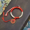 Pulsera tejida hecha a mano de color púrpura con diseño original, con monedas de cobre y hilo rojo
