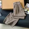 Toma real de pantalones largos casuales para mujer en un estilo relajado, con un patrón de cuadros retro color café, corte holgado, efecto adelgazante, diseño de pierna ancha y corte recto, para la colección de otoño 2026