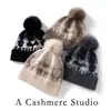 Nova coleção outono e inverno: gorro de tricô simples e versátil com pompom, feito de cashmere, apresentando um design color-block com um pequeno motivo de veado, oferecendo um visual moderno, casual e quente