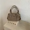 Bolso de axila versátil estilo coreano transfronterizo, moderno y de alta calidad, con un diseño texturizado tipo dumpling, acabado de gamuza y detalles de remaches, perfecto para ir al trabajo