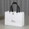 Bolsa de papel para envolver ropa de mujer con relieve de papel kraft, bolsa de mano para compras de regalo, logo impreso, en stock, envío gratis