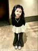 Top base de niña con volantes, estilo dos piezas falso, colección otoño 2026, top negro brillante con volantes estilo coreano de manga larga