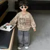 Conjunto de sudadera infantil estilo retro americano con efecto desgastado, bolsillos cargo tridimensionales y top con estampado de letras, junto con pantalones largos vaqueros rotos.