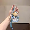 Llavero de oso de peluche con vestido floral rústico, con cuerda trenzada de colores y colgante de lazo de perlas, para bolsos de niñas