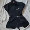 Camisa de verano INS transfronteriza negra con cuello alto y manga corta, botones metálicos, diseño único de ceñido a la cintura y abertura, top de estilo europeo y americano