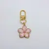 Chaveiro Pingente Flor de Cerejeira com Gotejamento de Óleo Liga Metálica Flor de Margarida Menina Fone de Ouvido Capa Bolsa Pingente