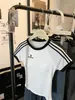 Camiseta Curta Feminina Verão Sexy Slimming Look Casual Retro Americano com Listras Contrastantes, Gola Redonda, Ombro Direito e Bojo