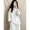 Foto real de una blusa blanca lisa para mujer, de manga larga, corte holgado, cuello redondo, estilo Zen, con botones, nueva colección Otoño 2026