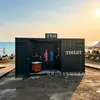 Baño-contenedor con acabado estilo industrial y rejillas de ventilación, inodoro público móvil económico para campamentos