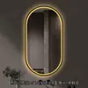 Espejo de baño inteligente ovalado en stock con lijado exterior e iluminación LED translúcida, adecuado para montaje en pared de baño y proyectos hoteleros, con opciones de personalización.