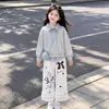 Elegante y a la moda conjunto de dos piezas para niñas para primavera y otoño: un top a rayas con un diseño de cuello único, combinado con pantalones casuales con delicados detalles de encaje - un conjunto de dos piezas moderno