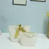 Saco de presente de papel Yuanbao Saco de presente com fita Saco de compras para roupas com placa de luz Saco de presente com corda de três fios logo impresso
