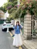 Conjunto de tres piezas de estilo coreano para primavera y otoño: chaleco de punto azul de manga corta con cordón, combinado con camisa base estampada floral y falda de cintura alta
