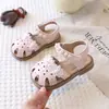 Sandálias Infantis Femininas Estilo Novo Verão 2026 Sapatos de Princesa Sapatos de Bebê Biqueira Fechada Flor Vazada Pérola Velcro Sandálias de Solado Macio