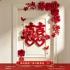 Nueva decoración de habitación de bodas estilo chino, con caracteres auspiciosos, decoraciones festivas para puertas, borlas y arreglos florales, creando un telón de fondo pintoresco para las fotos de boda.