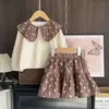 Ropa Infantil Coreana de Moda Transfronteriza Nuevo Estampado de Moño Camisa de Muñeca de Manga Larga Falda Corta Conjunto para Niñas Primavera y Otoño 2026