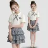 Conjunto de dos piezas de estilo universitario coreano para niñas con falda corta de cuadros, camiseta de manga corta de dibujos animados de verano y falda de pastel para niños mayores