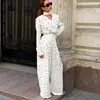 Conjunto de duas peças com camisa de gola V plissada, com design marcante, acinturado, e calça pantalona fluida, com estampa de bolinhas retrô francesa.