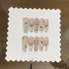 Un par de uñas postizas estilo francés hechas a mano, con diseño degradado rosa nude y crema de leche de coco, estilo ojo de gato talladas y adornadas.