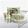 Tazón de té de cerámica texturizado de col blanca tridimensional con pico, emparejado con un soporte para batidor de té del mismo color, múltiples accesorios para la preparación de matcha