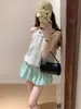 Falda corta de estilo suave con capullo verde para mujer, nueva falda de línea A adelgazante para el verano de 2026, minifalda esponjosa para petite