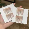 Un Set de Uñas con un Degradado Ámbar Ligeramente Borracho, Polvo Blanco Leche, Estilo Francés y Pedrería de Corazones Cromados