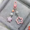 Hebilla de puerta G05 nuevo acrílico hueco brillante estrella de cinco puntas llavero para coche colgante crema dos colores campanilla a juego
