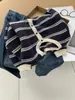 Um cardigã de tricô listrado azul marinho, estiloso e retrô, para mulheres, perfeito para a primavera e o outono. Possui um tecido macio e amigo da pele, um design vazado, decote redondo e detalhes de botões.