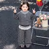 Conjunto otoñal estilo bosque para niñas, nueva colección 2026, muy elegante, con una chaqueta con capucha y pantalones a rayas de color gris oscuro.