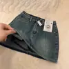 Mini saia jeans de cintura alta estilo retrô de Hong Kong para mulheres, novo modelo 2026, anti-exposição, corte A, justa ao quadril, emagrecedora, versátil, moderna, cor sólida