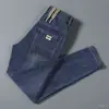 Calça jeans de sarja elástica para primavera e outono, estilo coreano slim fit, marca da moda, bordado simples, calça casual moderna e versátil para homens
