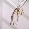 Colgante de bolso estilo vacacional transfronterizo de rafia tejida de colores con llavero de estrella de mar de cuerda tejida a mano color dopamina